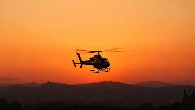 FLUX 3 Klein example: A helicopter silhouetted against an orange sunset sky above dark rolling hills.