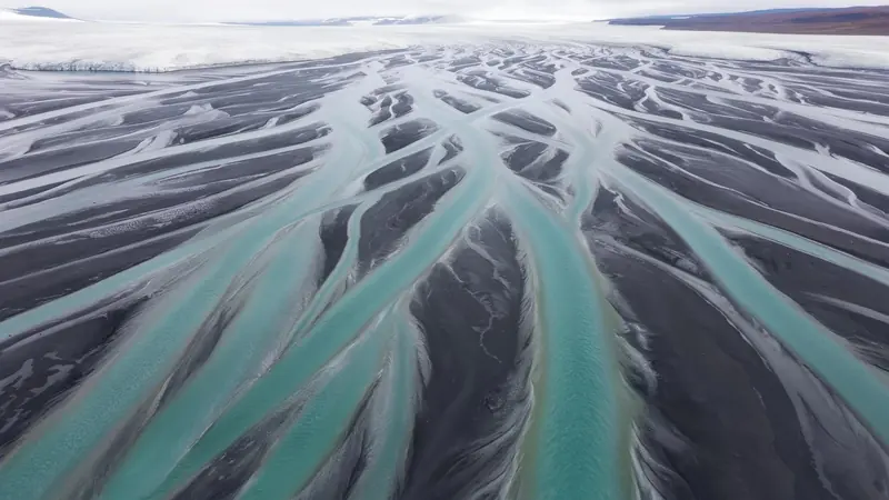 FLUX 3 Klein example: Aerial photograph of a braided glacial river delta, turquoise channels weaving through black sand.