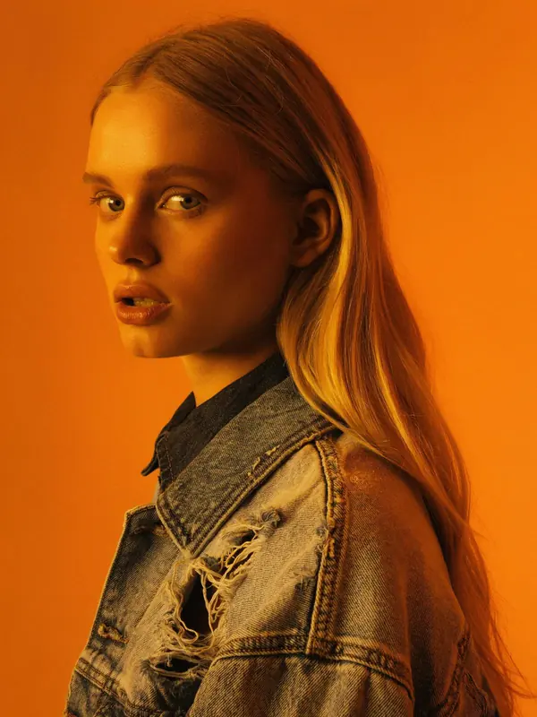 FLUX 3 Klein example: Portrait of a woman in a denim jacket against orange