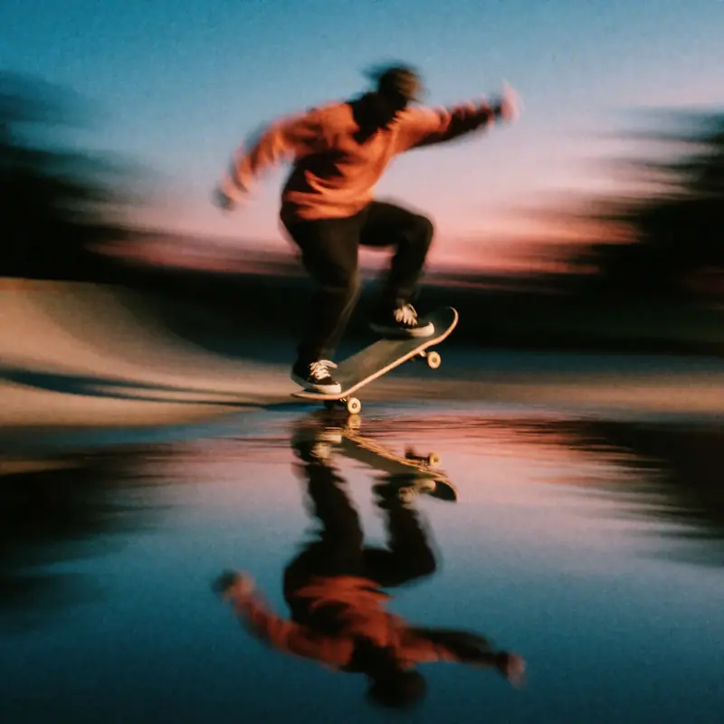 Krea 2 example: A skateboarder doing a kickflip at blue hour, a puddle reflects the skateboarder. ethereal motion blur style